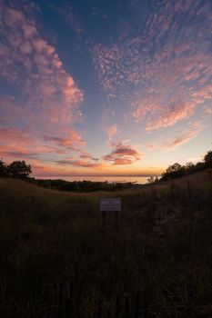 Stunning sunset view from Mount Pisgah, Holland, Michigan featuring a rustic dune fence and vibrant sky.