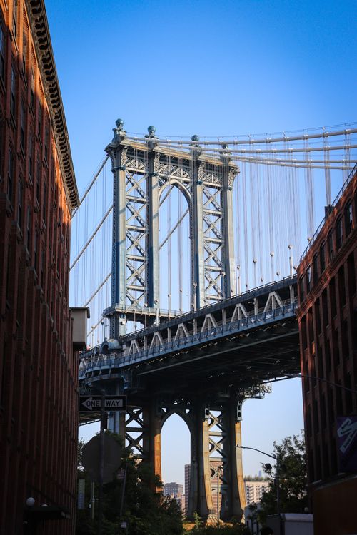 Free Captivating view of Manhattan Bridge framed by Brooklyn buildings, under blue sky. Stock Photo