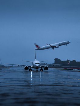 Airplanes on a rainy runway in Thiruvananthapuram, India, with one taking off.