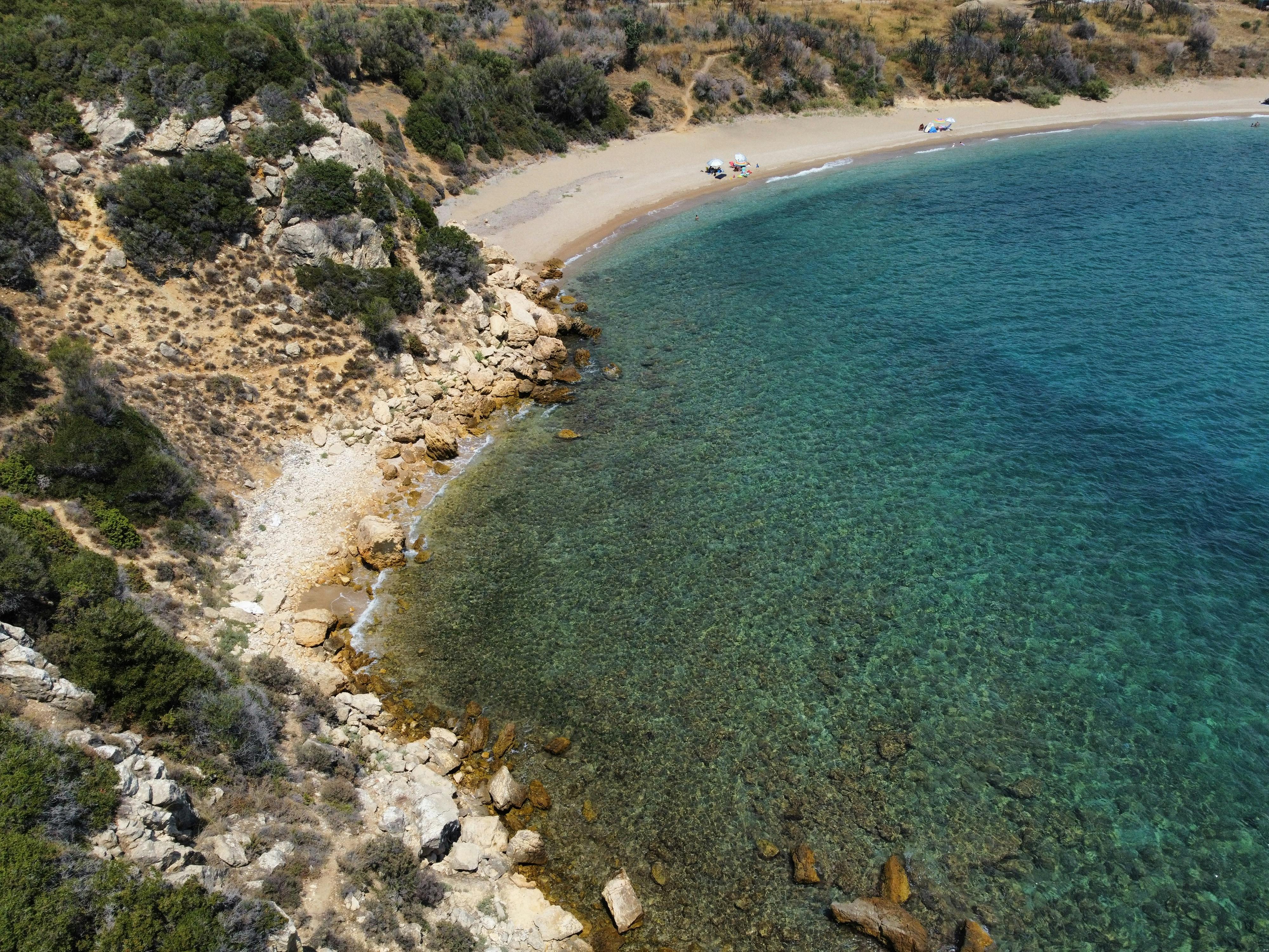 Aerial shot of a serene beach cove with clear turquoise waters and rocky shoreline.