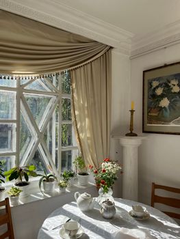 A charming dining area with plants and classic decor, bathed in natural sunlight.