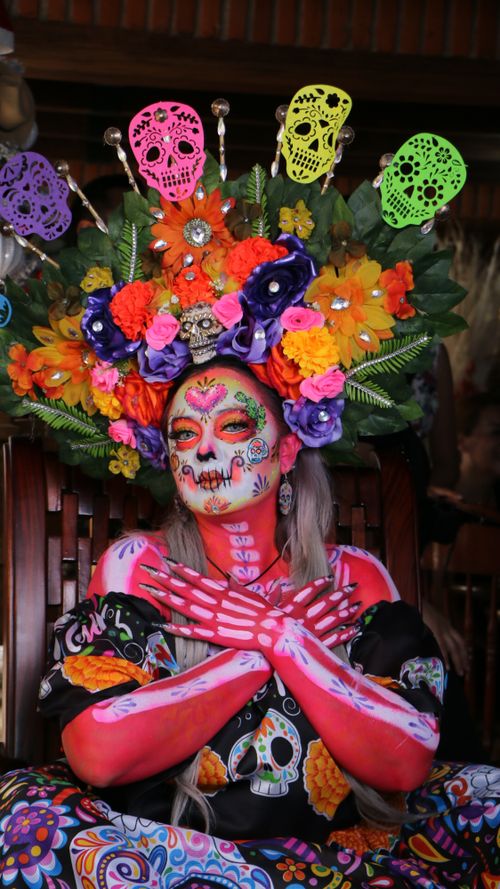 Free Colorful Day of the Dead makeup and costume featuring floral crown and vivid face painting. Stock Photo