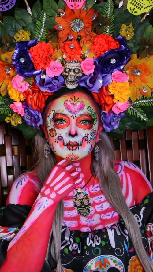 Free Colorful portrait of a person with Dia de los Muertos face paint and floral headpiece. Stock Photo