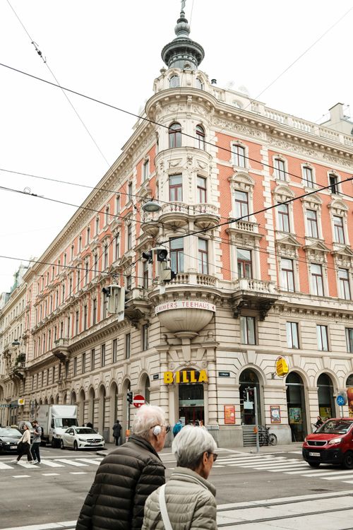 Free A historic building in Vienna with people crossing the street, featuring classic European architecture. Stock Photo