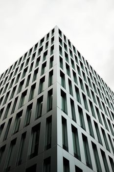 Close-up view of a modern skyscraper facade with geometric design, featuring a bright overcast sky.