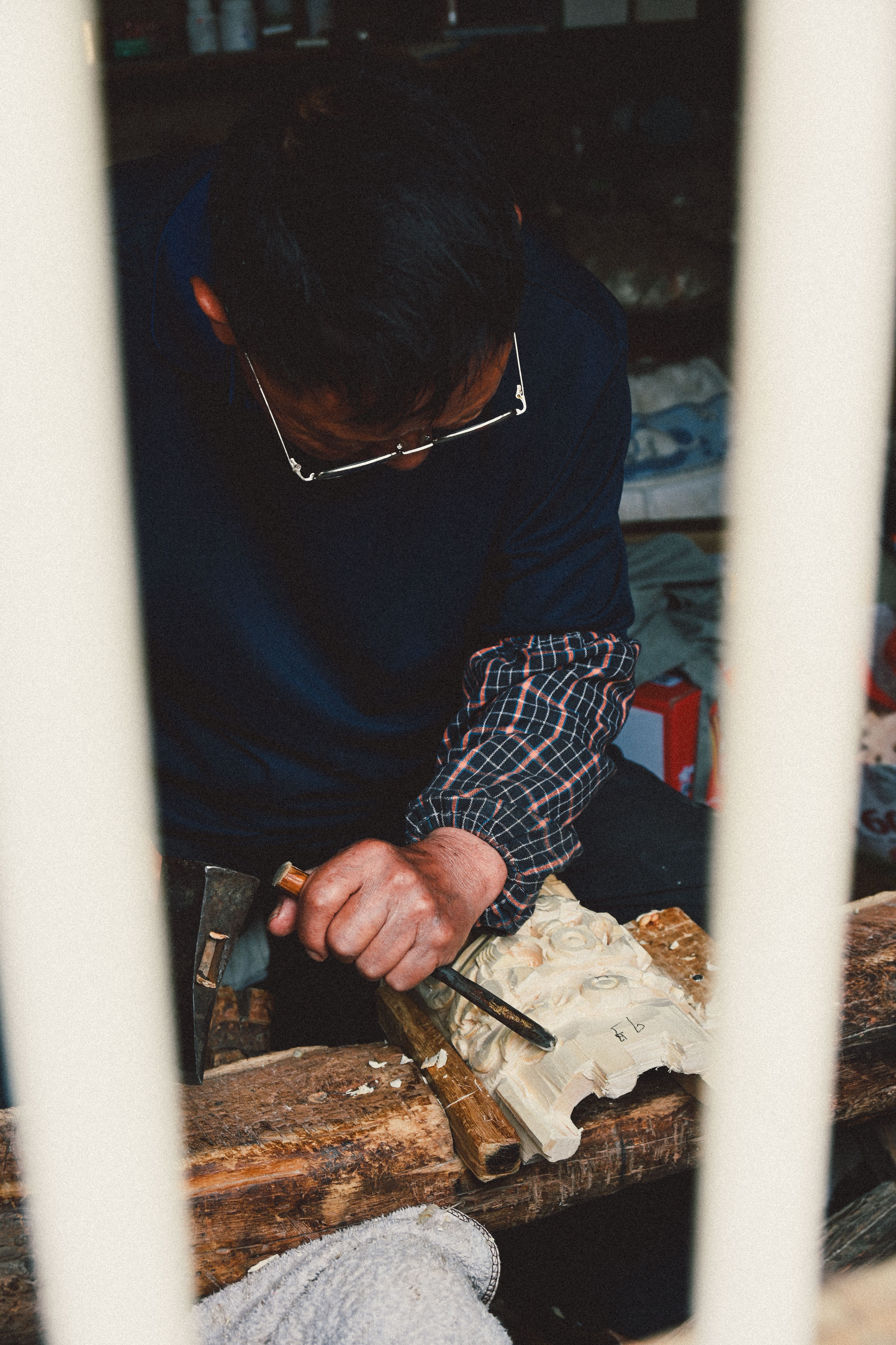 Close-up of artisan expertly carving wood piece indoors, showcasing craftsmanship.
