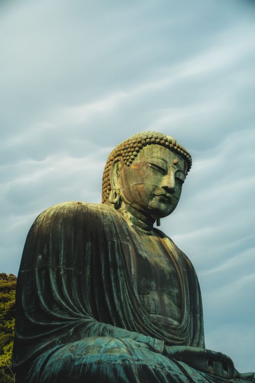 Free Majestic Great Buddha statue of Kamakura with serene and dramatic sky backdrop. Stock Photo
