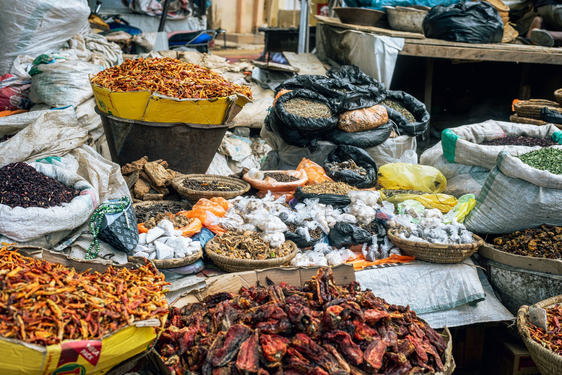 Vibrant display of diverse spices and herbs at an outdoor market stall.
