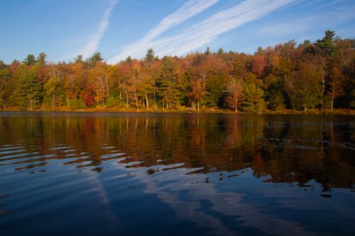 Free Serene autumn scene with vibrant foliage reflecting on a lake under a blue sky in Johnstown, New York. Stock Photo