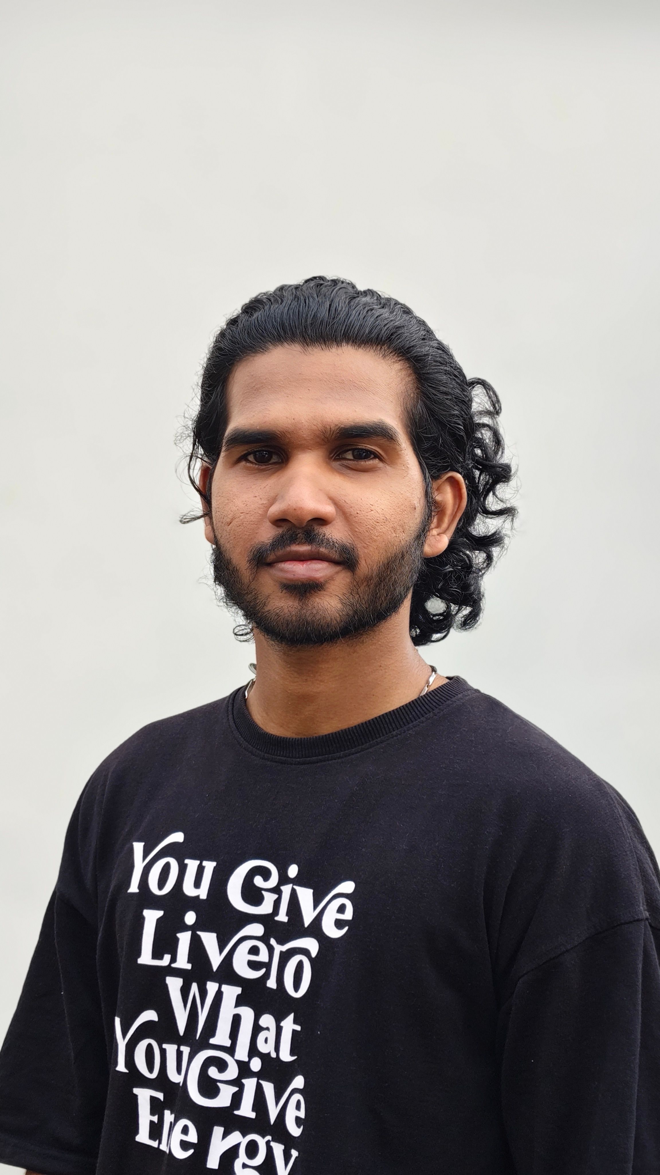Casual portrait of a young man in a black t-shirt with motivational text.