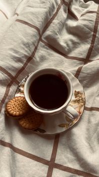 A warm cup of tea with biscuits on a bed. Perfect cozy morning setup.