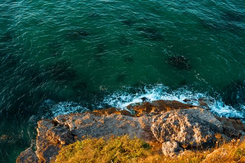 Free Dramatic view of the rocky coastline in Kırklareli, Türkiye with waves crashing under a vibrant sunset. Stock Photo