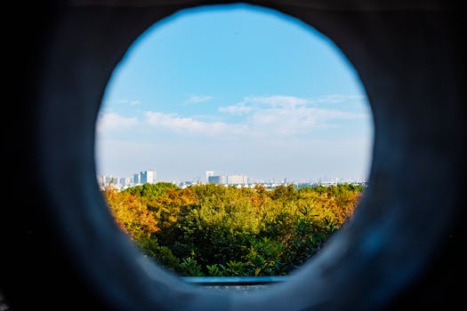 Catch a unique perspective of Suzhou cityscape viewed through a round opening, blending urban and natural landscapes.