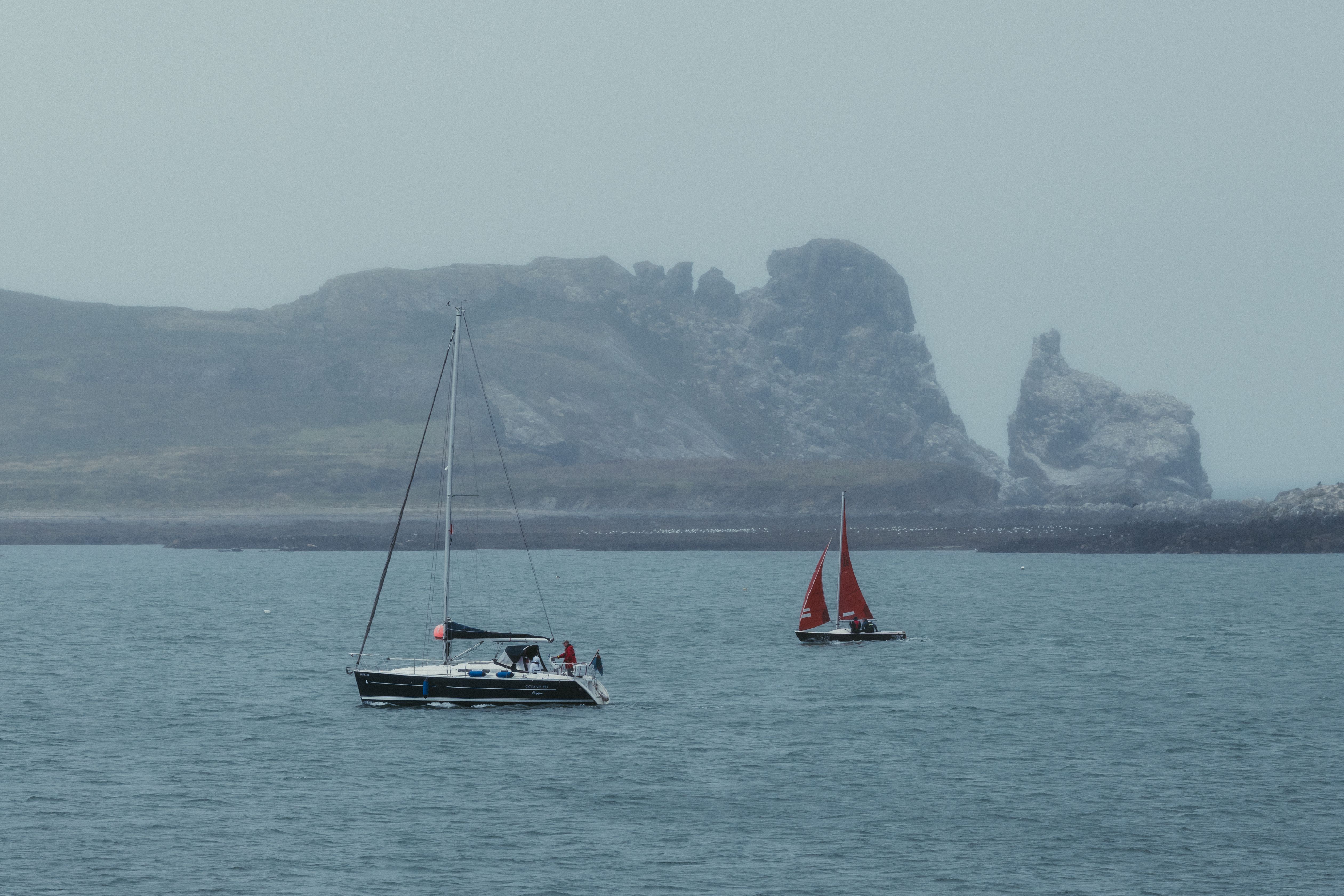 Serene sailboats on the misty waters of Howth Harbor in Dublin Bay, Ireland.