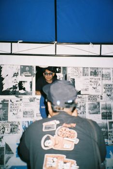 Person capturing a vendor at an urban art stand with posters. - Fotografer Sidoarjo