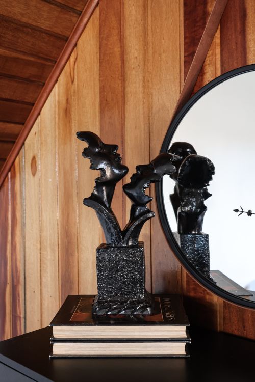 Free Black abstract sculpture on books with mirror reflection, wooden background. Stock Photo