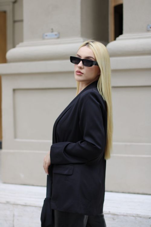 Free Stylish woman with long blonde hair wearing sunglasses, posing outside in a black blazer. Stock Photo