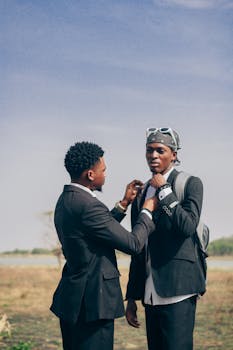 Two young men in suits, engaging outdoors in Zaria, Nigeria, displaying friendship.