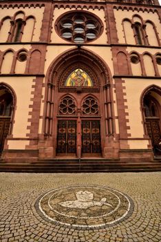 Arched entrance of a Gothic church with stained glass in Freiburg, Germany.
