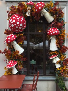 Charming window decoration featuring red and white spotted mushrooms and autumn leaves.