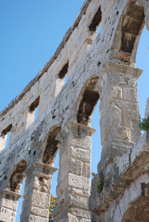 Free Close-up of the ancient Roman amphitheater arches in Pula, Croatia under a clear blue sky. Stock Photo