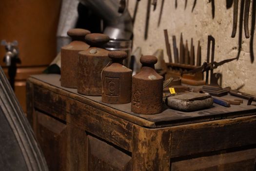 Old iron weights on a wooden table in a rustic workshop. Perfect for vintage themes.
