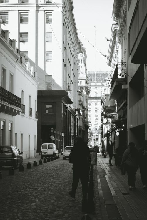 Free Monochrome view of an urban street with pedestrians and tall buildings. Stock Photo