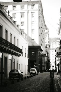 Charming black and white city street scene featuring historic architecture and parked cars.
