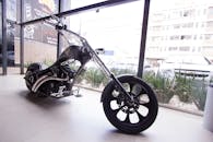 陈列室里，一辆现代的黑色斩波器摩托车在大玻璃窗前展示，窗外是城市景观