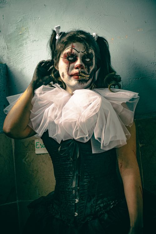 Free Striking makeup art featuring clown-inspired macabre look in dramatic lighting. Stock Photo