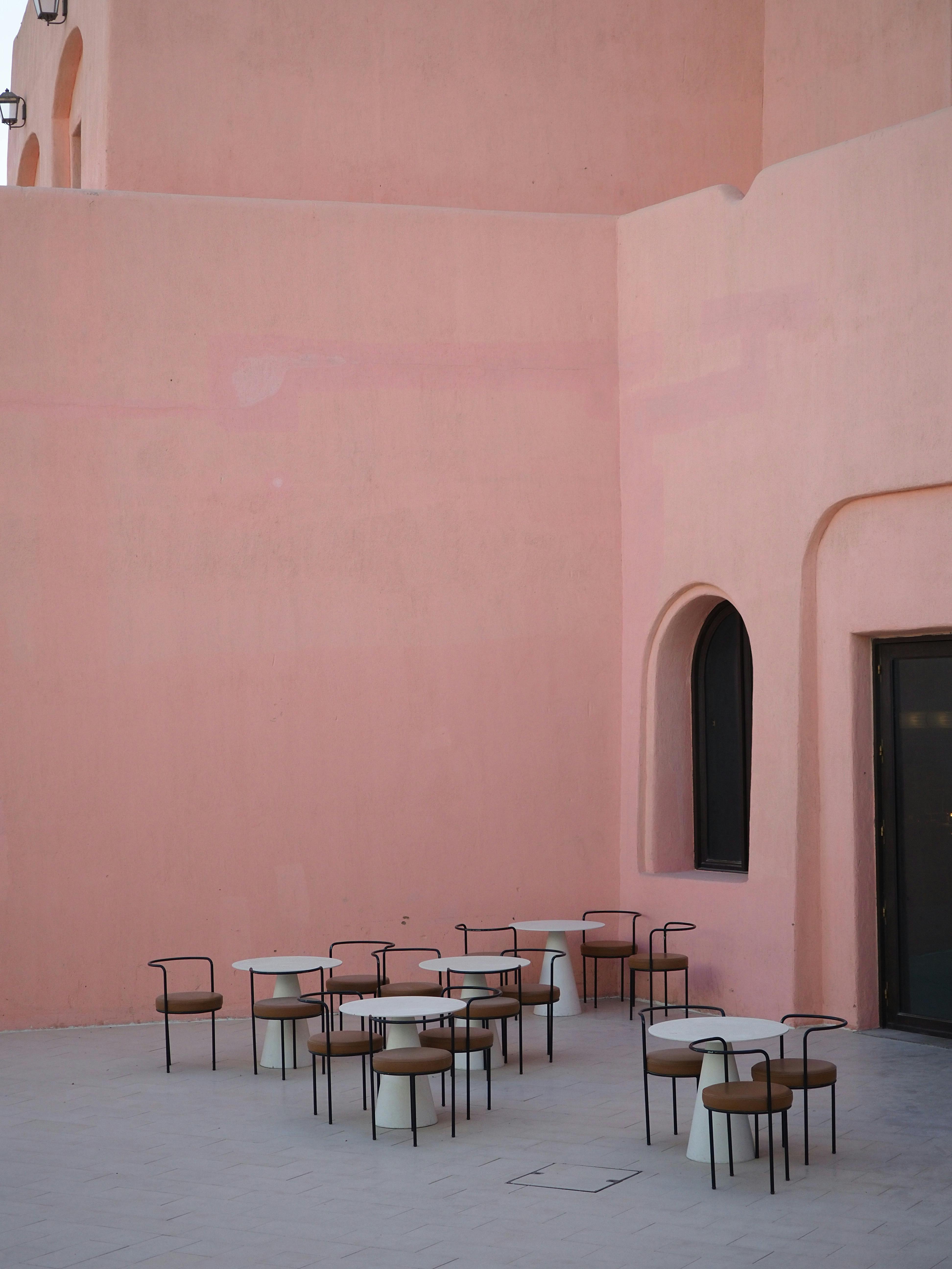 Empty outdoor cafe in Doha with pink walls and modern minimalist style, highlighting architectural charm.