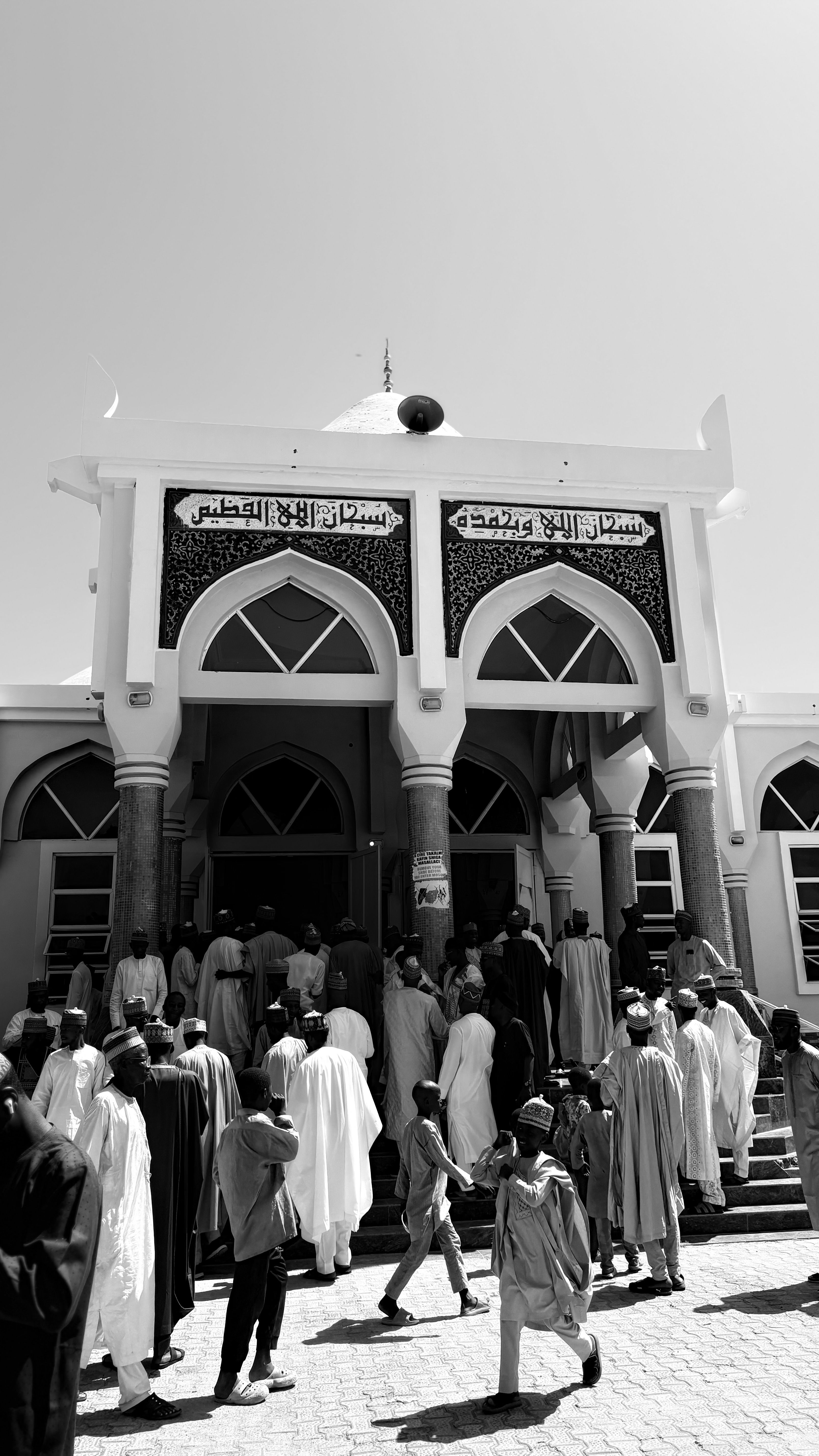 A group of people gathered outside a mosque, showcasing Islamic architecture.
