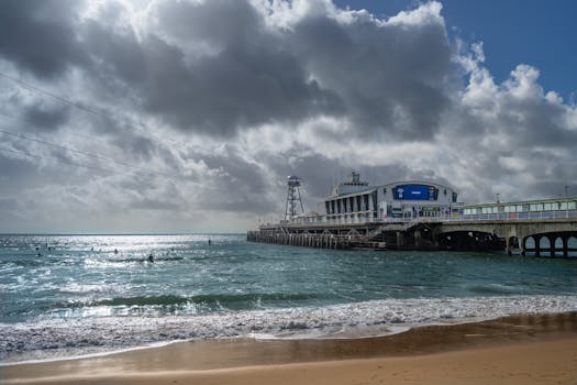 Moody clouds over Bournemouth Pier, England, with paddle boarders in the sea.