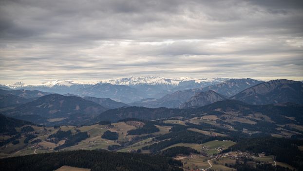 Aerial view of picturesque mountain range with snow-capped peaks under cloudy skies., free online jigsaw puzzle on JigsawPuzzlesFreeOnline.org