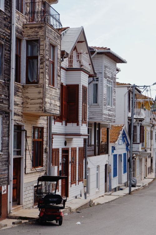 Free Quaint street with rustic wooden houses and a parked scooter, exuding historic charm. Stock Photo