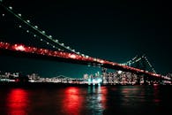 灯火通明的吊桥横跨水面，展现出夜市场景的活力