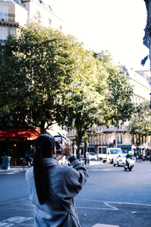 Free An adult woman photographs a bustling city street with her smartphone. Stock Photo