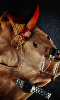 Stylish flat lay featuring a brown sweater, leather belt, wristwatch, and fragrance bottle.