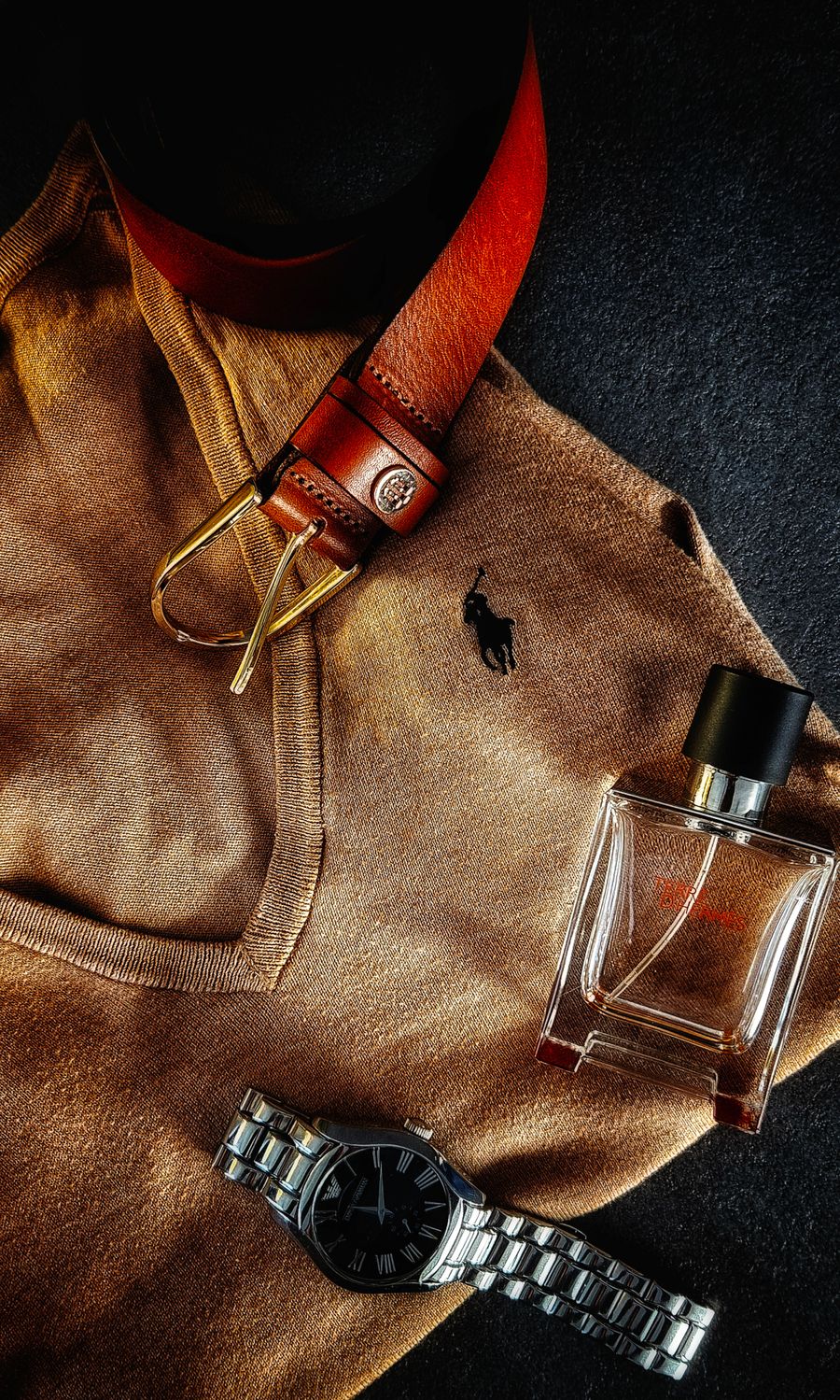 Men's fashion accessories flat lay with brown sweater, leather belt, watch and fragrance
