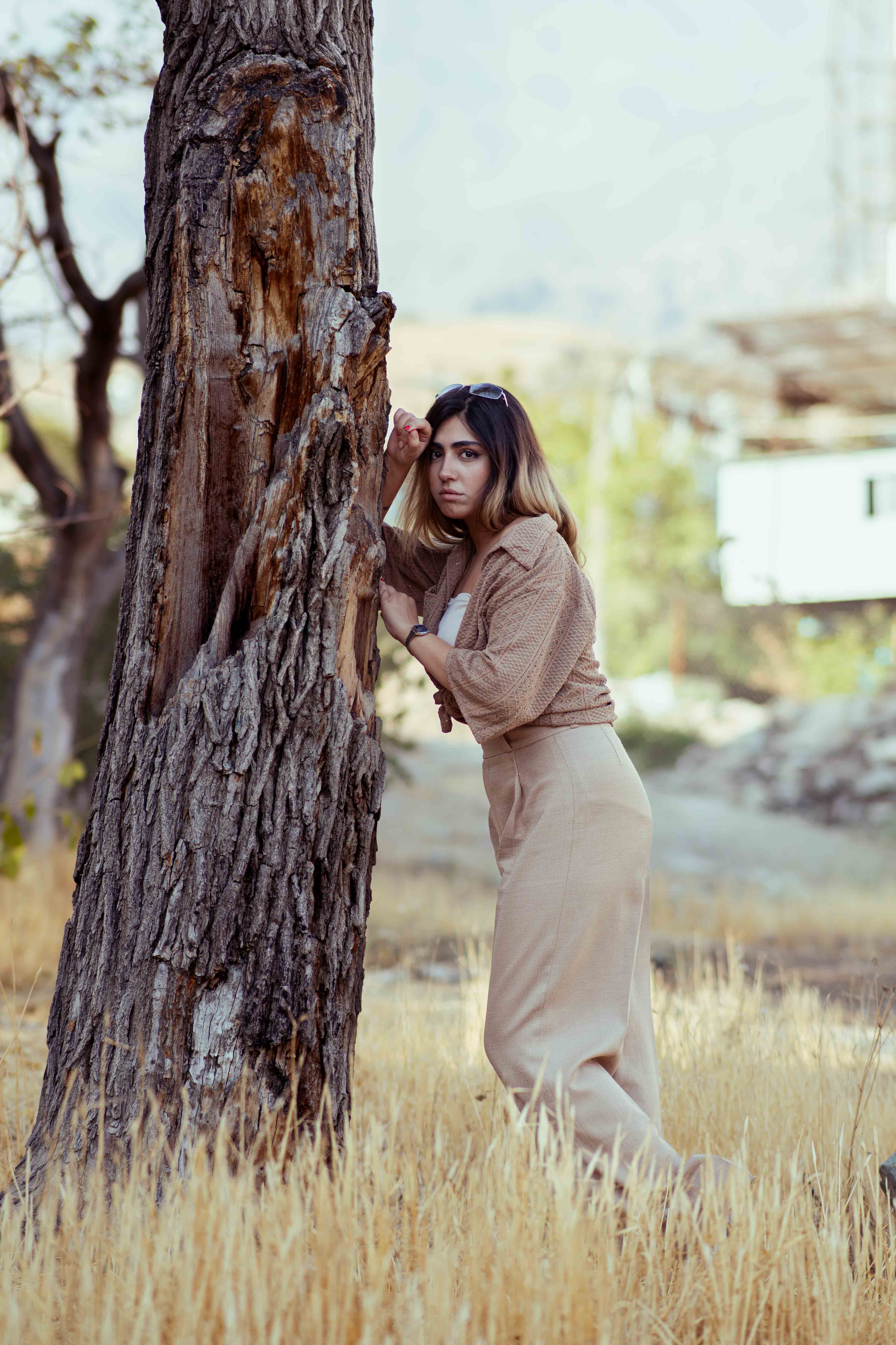 An elegant outdoor portrait of a woman leaning on a tree in Tehran, Iran.