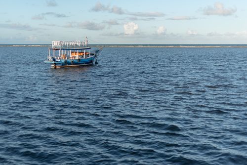 Free A tranquil scene of a blue boat floating on calm ocean waters in Arraial d'Ajuda, Bahia, Brazil. Stock Photo