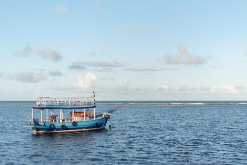 Free Peaceful beach setting in Arraial d'Ajuda, Bahia, with a lone boat under clear blue skies. Stock Photo