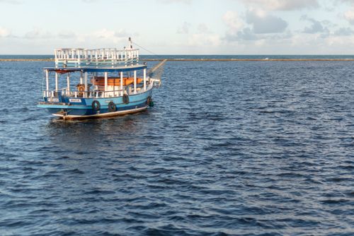 Free A scenic view of a blue boat floating on the ocean near Arraial d'Ajuda, Bahia, Brazil, during sunset. Stock Photo