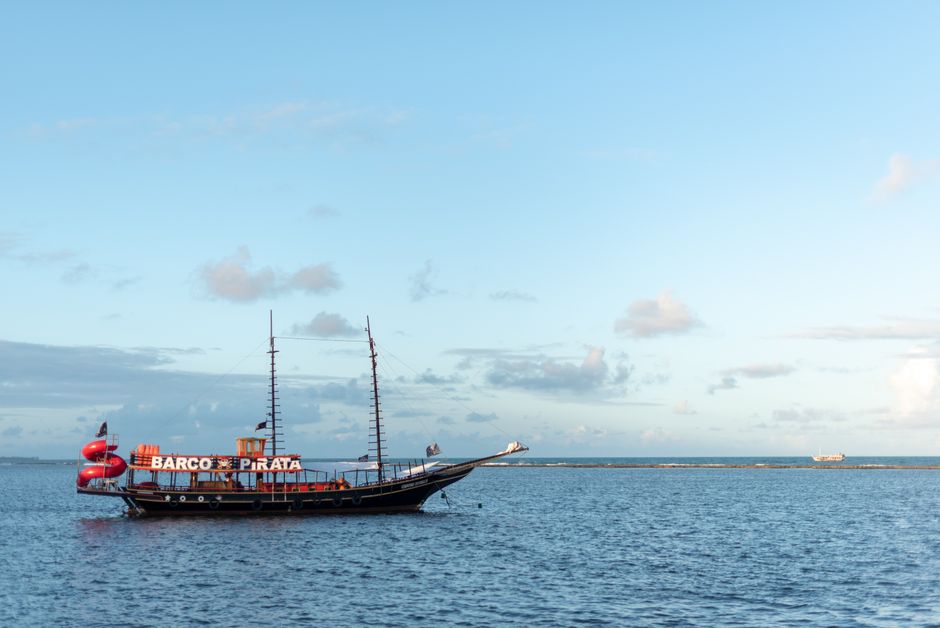A picturesque pirate ship sails on the tranquil waters of Arraial d'Ajuda, Bahia, Brasil.