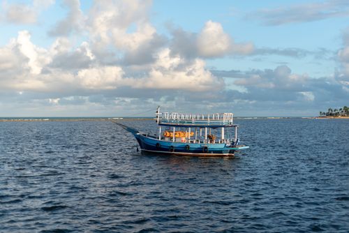 Free A picturesque blue boat floating in the tranquil waters of Arraial d'Ajuda, Bahia, Brazil under a cloudy sky. Stock Photo