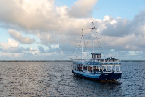 Free A serene view of a traditional boat floating on the calm ocean in Arraial d'Ajuda, Bahia, Brazil. Stock Photo