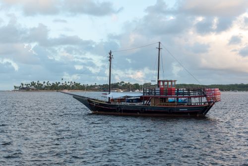 Free Scenic view of a traditional boat sailing near Arraial d'Ajuda, Bahia, against a cloudy sky. Stock Photo