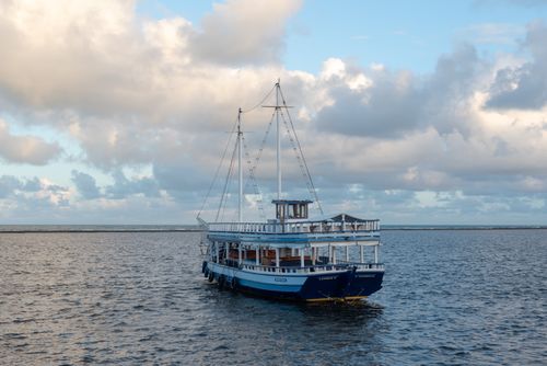 Free Charming boat sailing through calm waters in Arraial d'Ajuda, Bahia, under a cloudy sky. Stock Photo