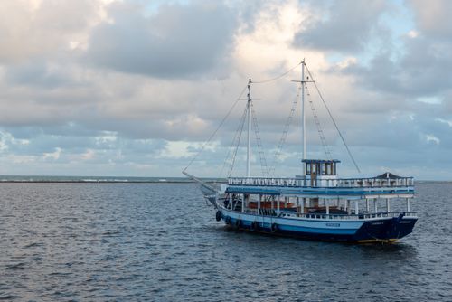Free A peaceful boat floats on calm waters in Arraial d'Ajuda, Bahia, under a cloudy sky. Stock Photo