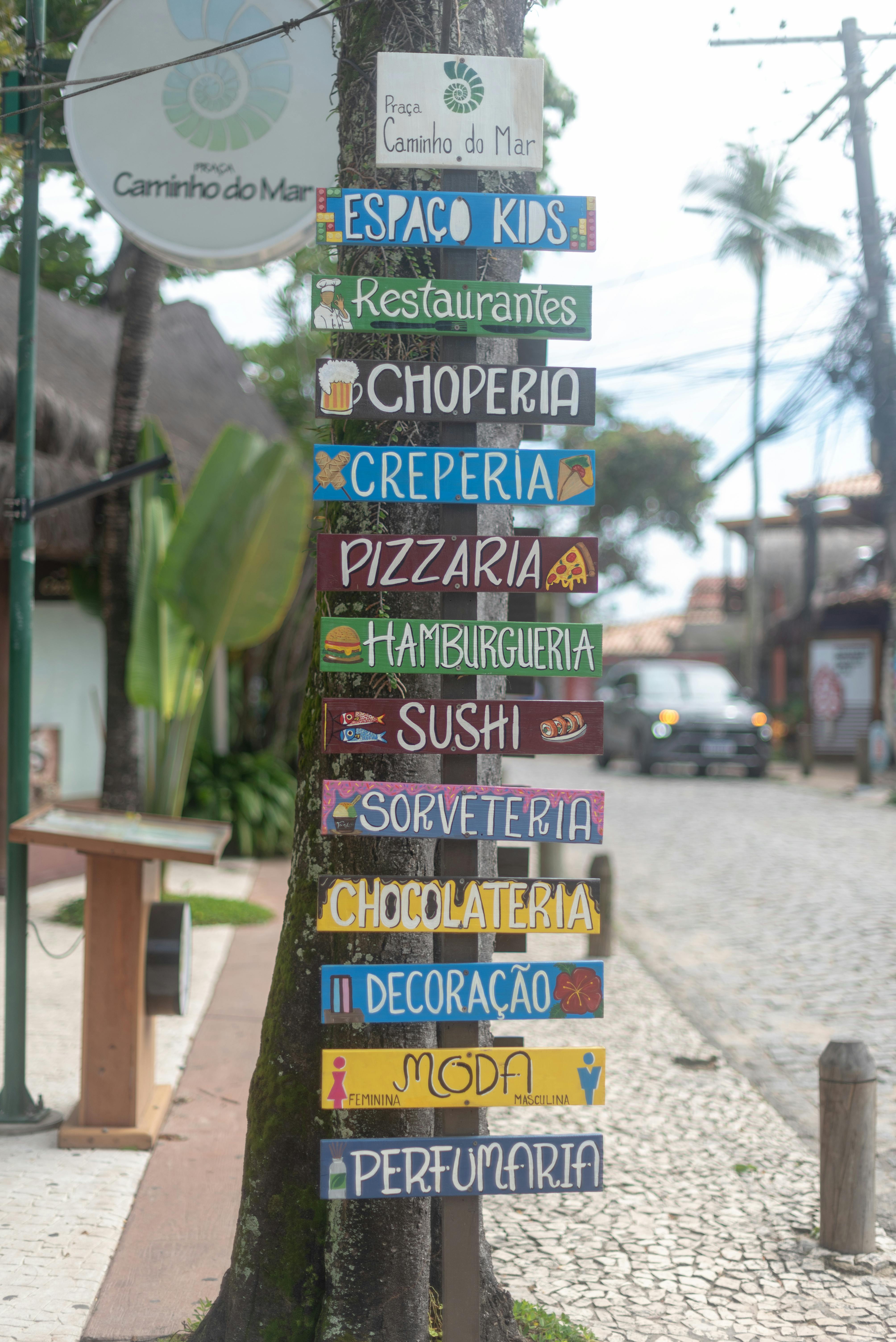 Gratuit Indicator vibrant în Arraial d'Ajuda, Bahia, care direcționează către diverse afaceri pe o stradă pietruită. Fotografie de stoc